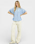 Woman wearing a light blue blouse and white pants on a white background