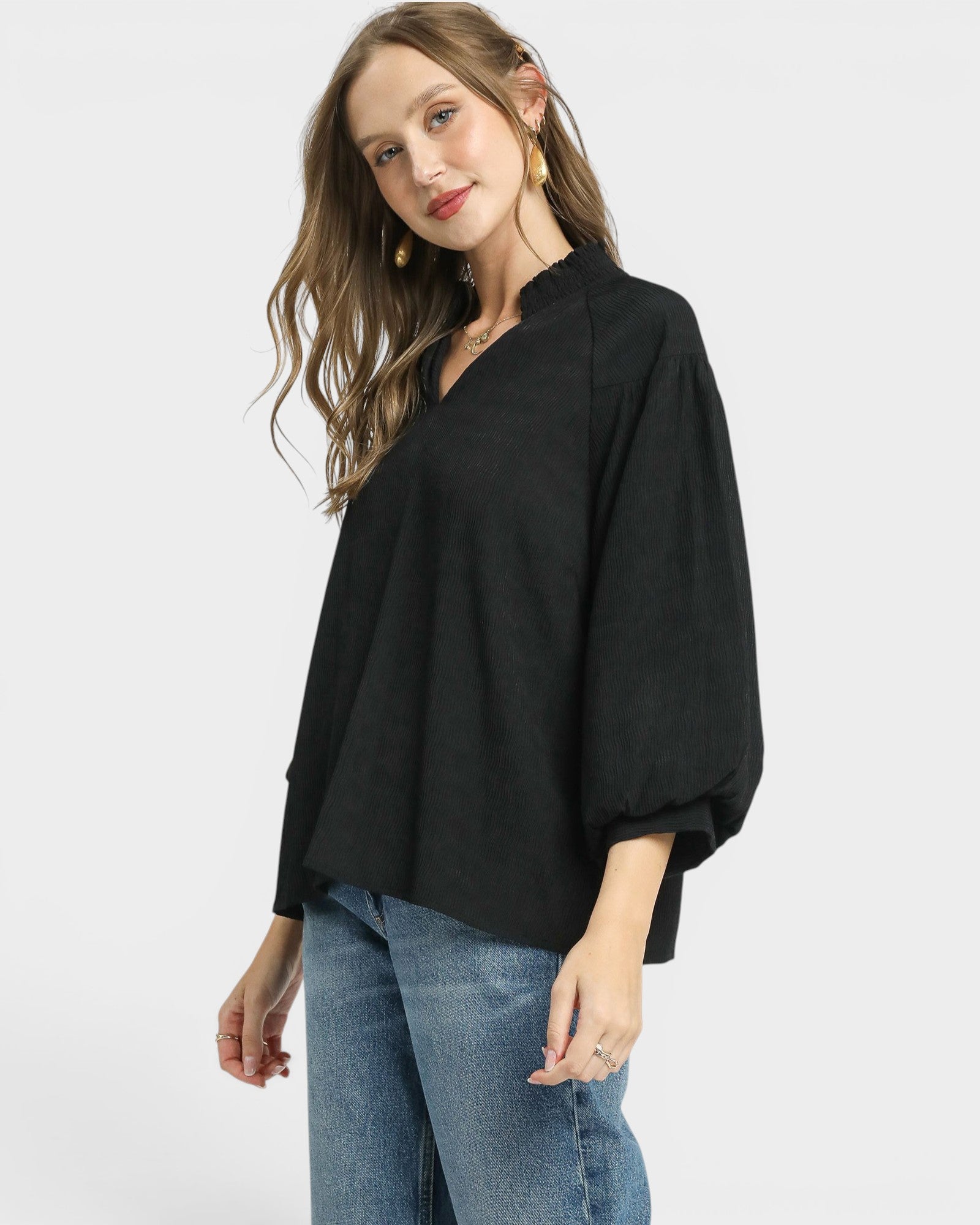 Woman wearing a black top and blue jeans on a white background