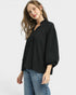 Woman wearing a black top and blue jeans on a white background