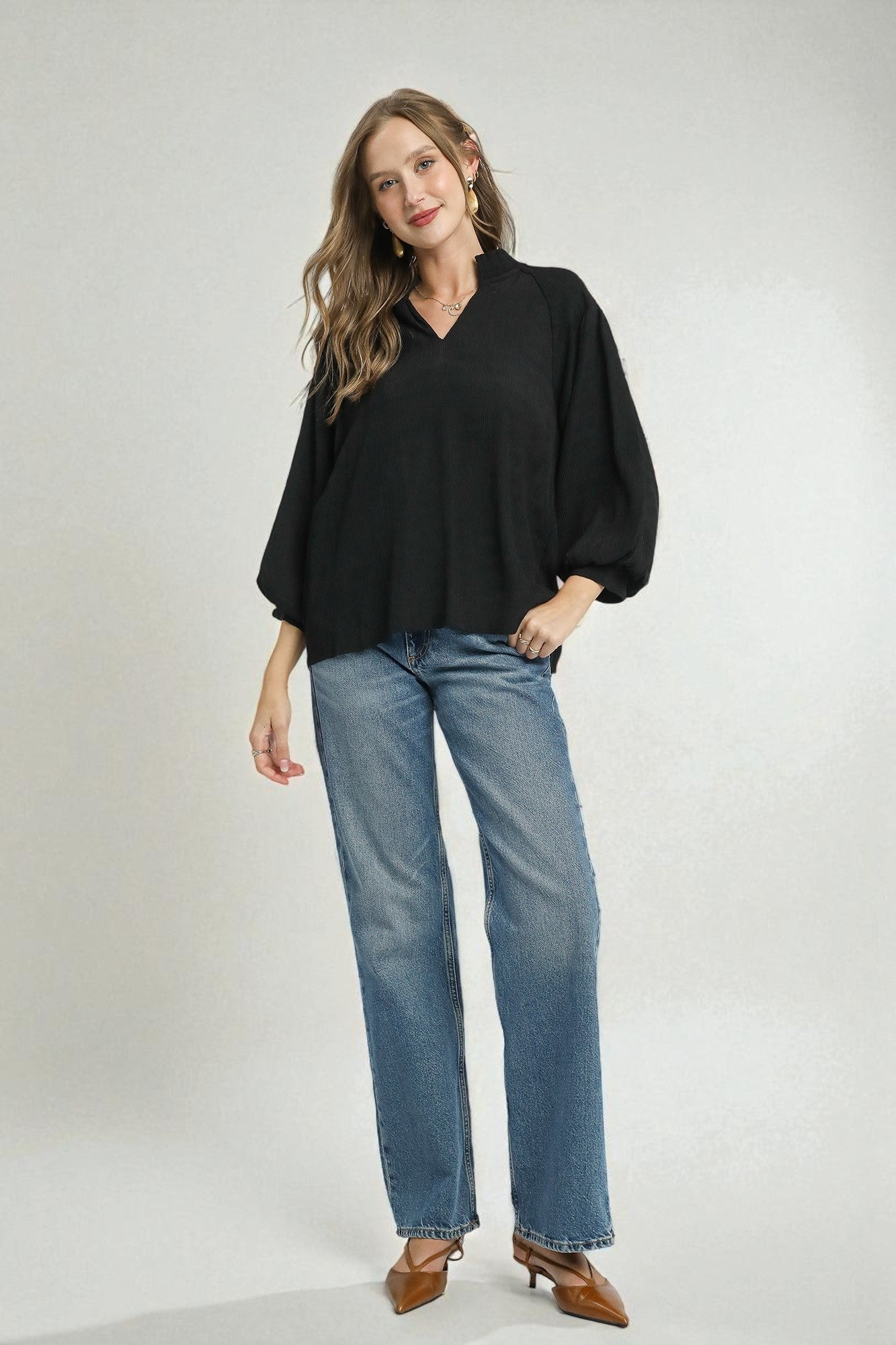 Woman wearing a black blouse and blue jeans on a white background