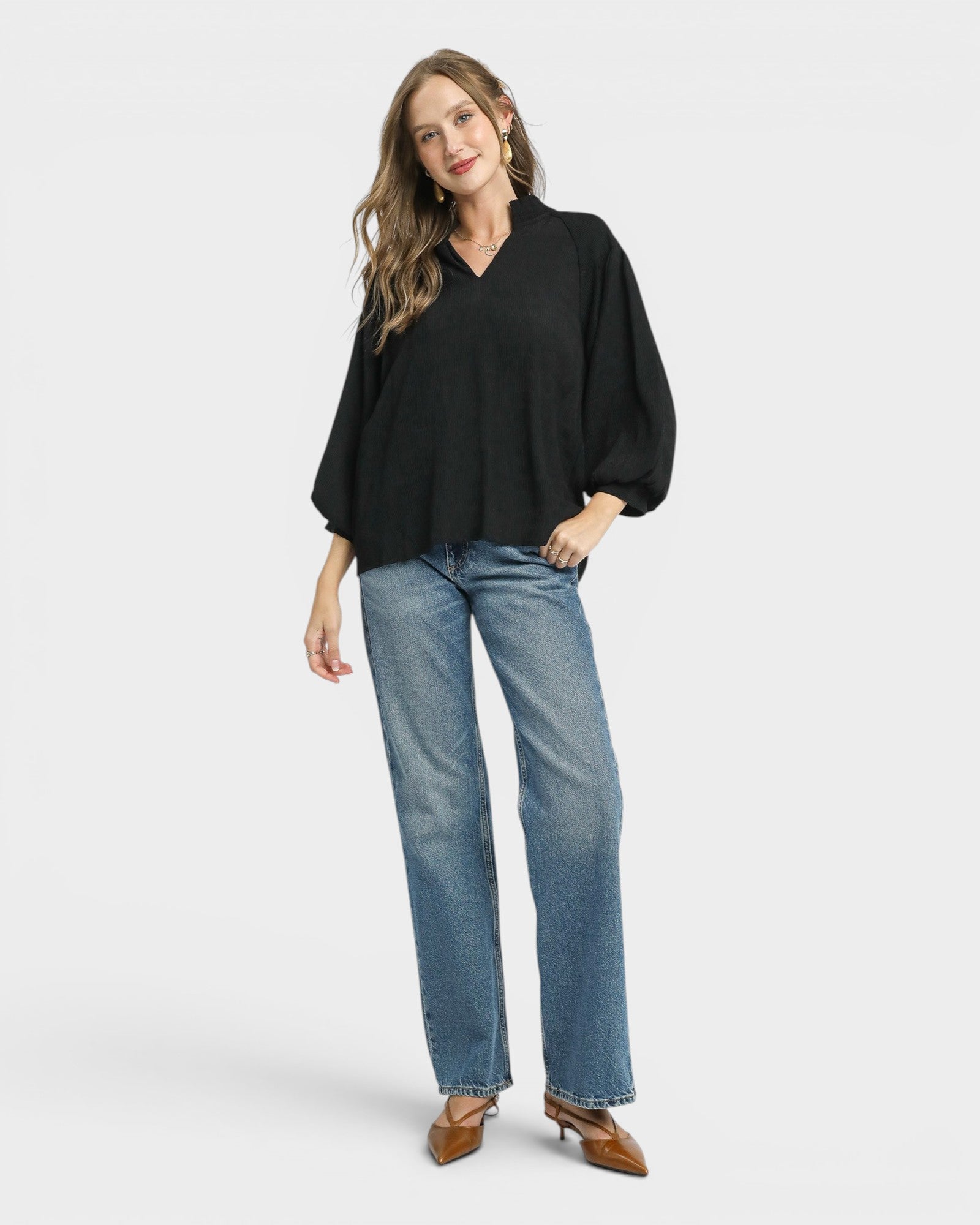Woman wearing a black blouse and blue jeans on a white background