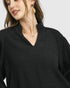Woman wearing a black top with a plain background