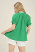 Woman wearing a green blouse and white shorts on a beige background