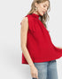 Woman wearing a red sleeveless top with a bow detail on a white background