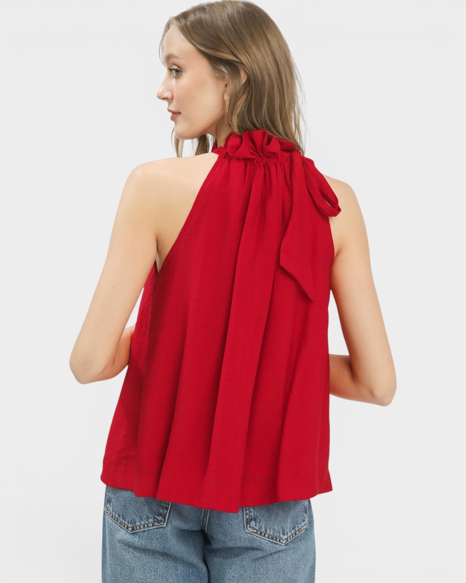 Woman wearing a red halter top with a bow detail on a white background