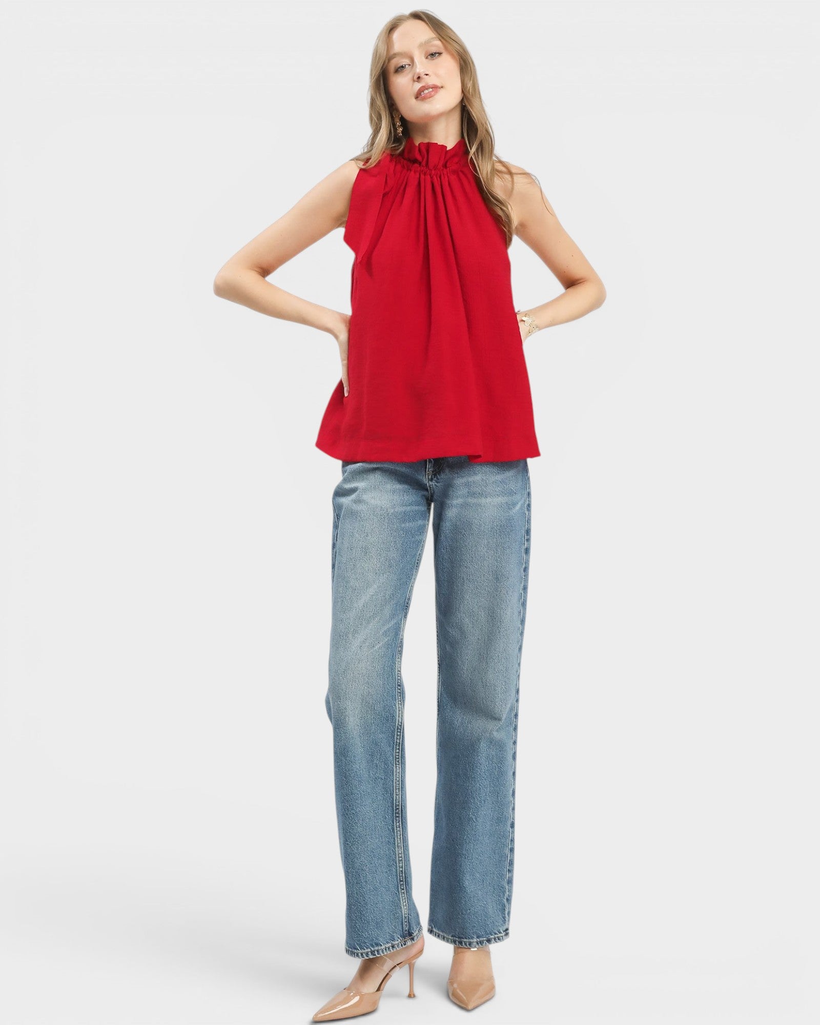 Woman wearing a red sleeveless top and blue jeans on a white background