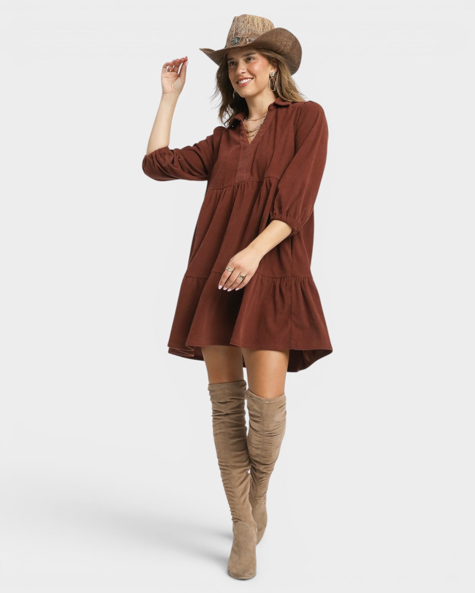 Woman wearing a brown dress and tan boots on a white background