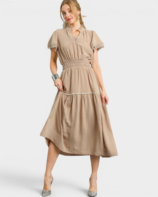 Woman wearing a beige dress with white trim on a white background