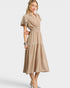 Woman wearing a beige dress with lace trim on a white background