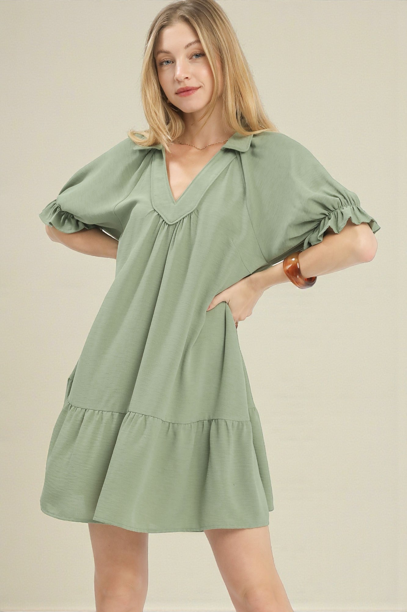 Woman wearing a green dress against a beige background
