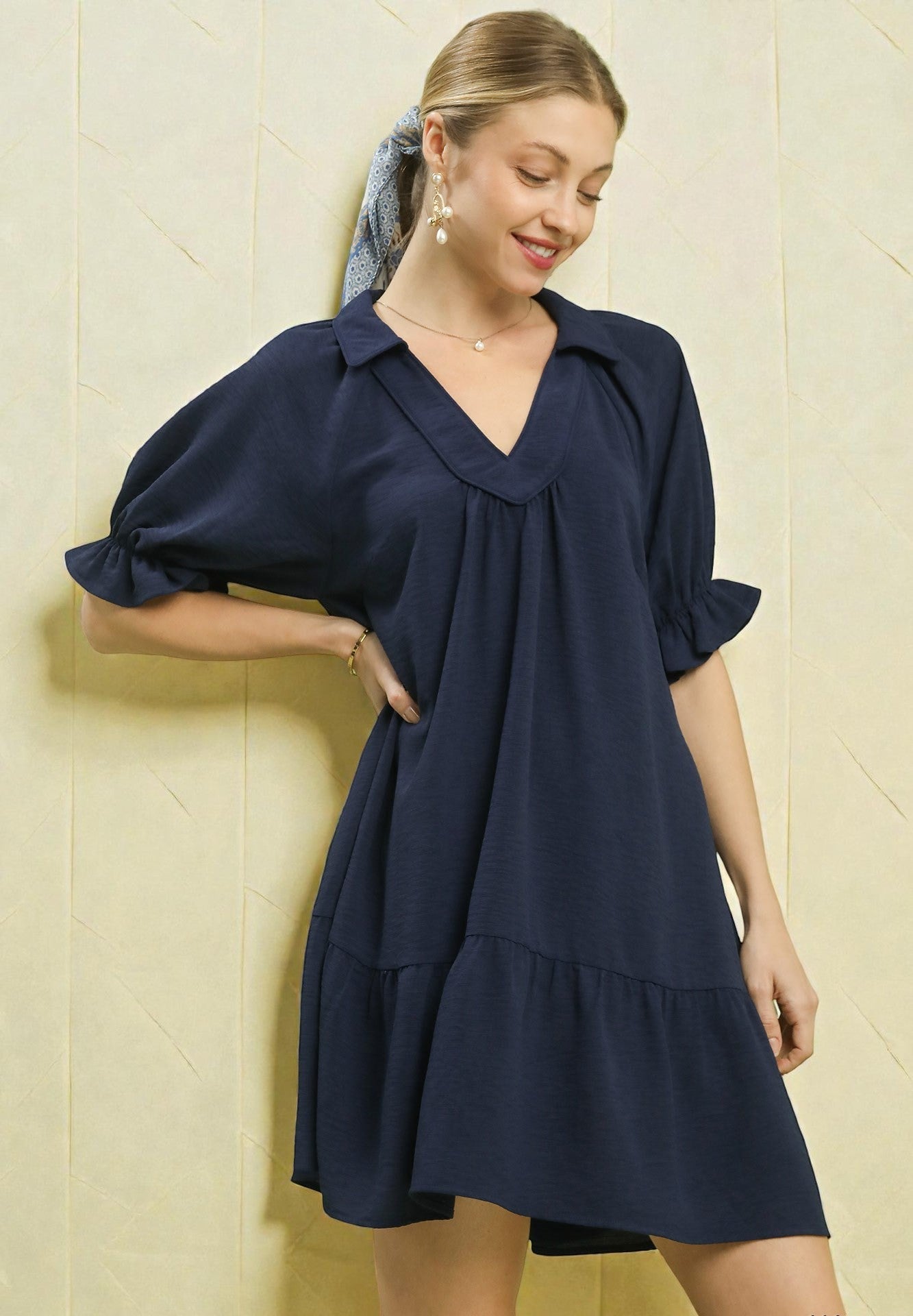 Woman wearing a navy blue dress against a beige wall