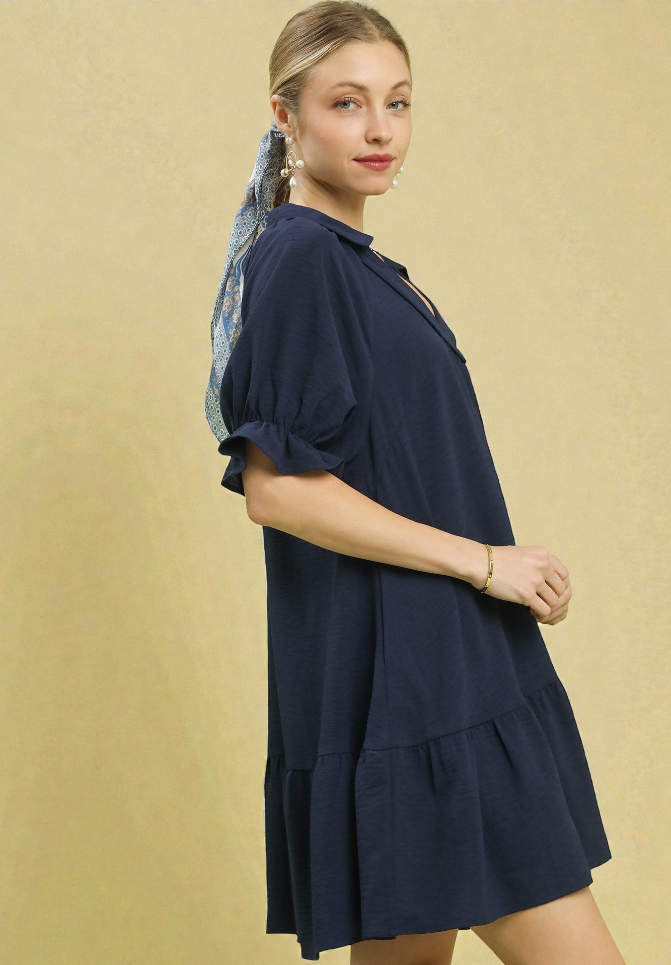 Woman wearing a navy blue dress against a beige background