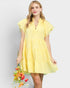 Woman wearing a yellow dress holding flowers against a light gray background