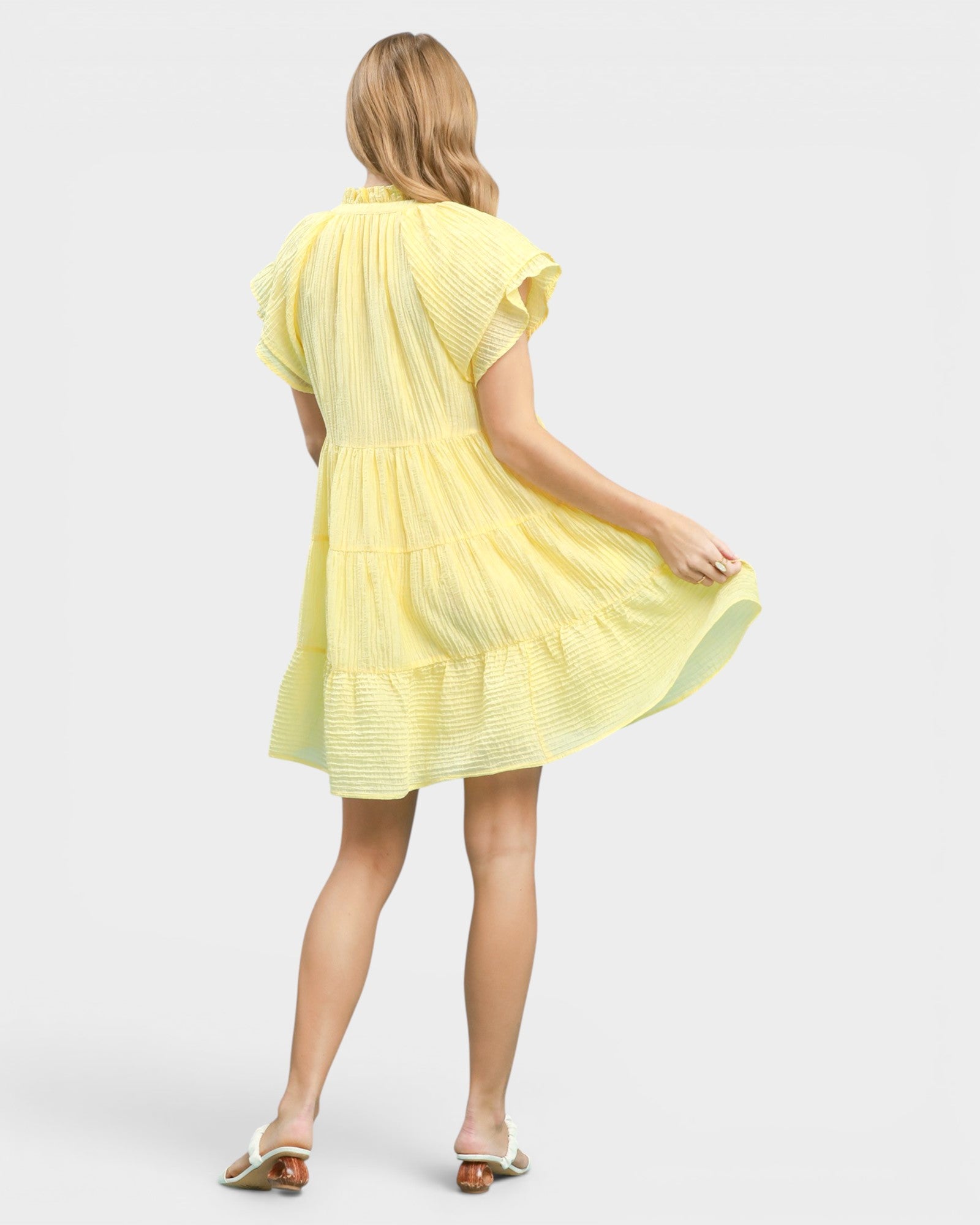 Woman wearing a yellow dress on a plain background