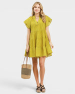 Woman wearing a yellow dress holding a striped bag on a white background