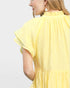 Yellow pleated dress worn by a person on a light gray background