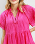Close-up of a person wearing a bright pink dress with a plain background