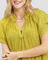 Woman wearing a yellow pleated dress with a plain background
