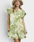 Woman wearing a green and white floral dress with a plain background