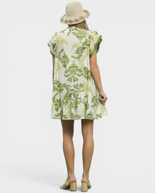 Woman wearing a green and white floral dress with a hat on a white background