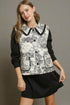 Woman wearing a black and white patterned blouse with a black skirt against a gray background