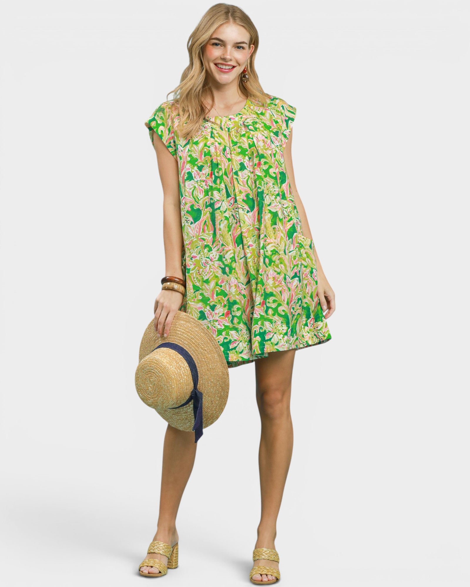 Woman wearing a floral dress holding a straw hat on a white background