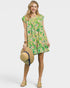 Woman wearing a floral dress holding a straw hat on a white background