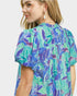 Woman wearing a colorful floral blouse with a white background