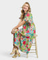 Woman wearing a colorful floral dress sitting on a stool against a white background