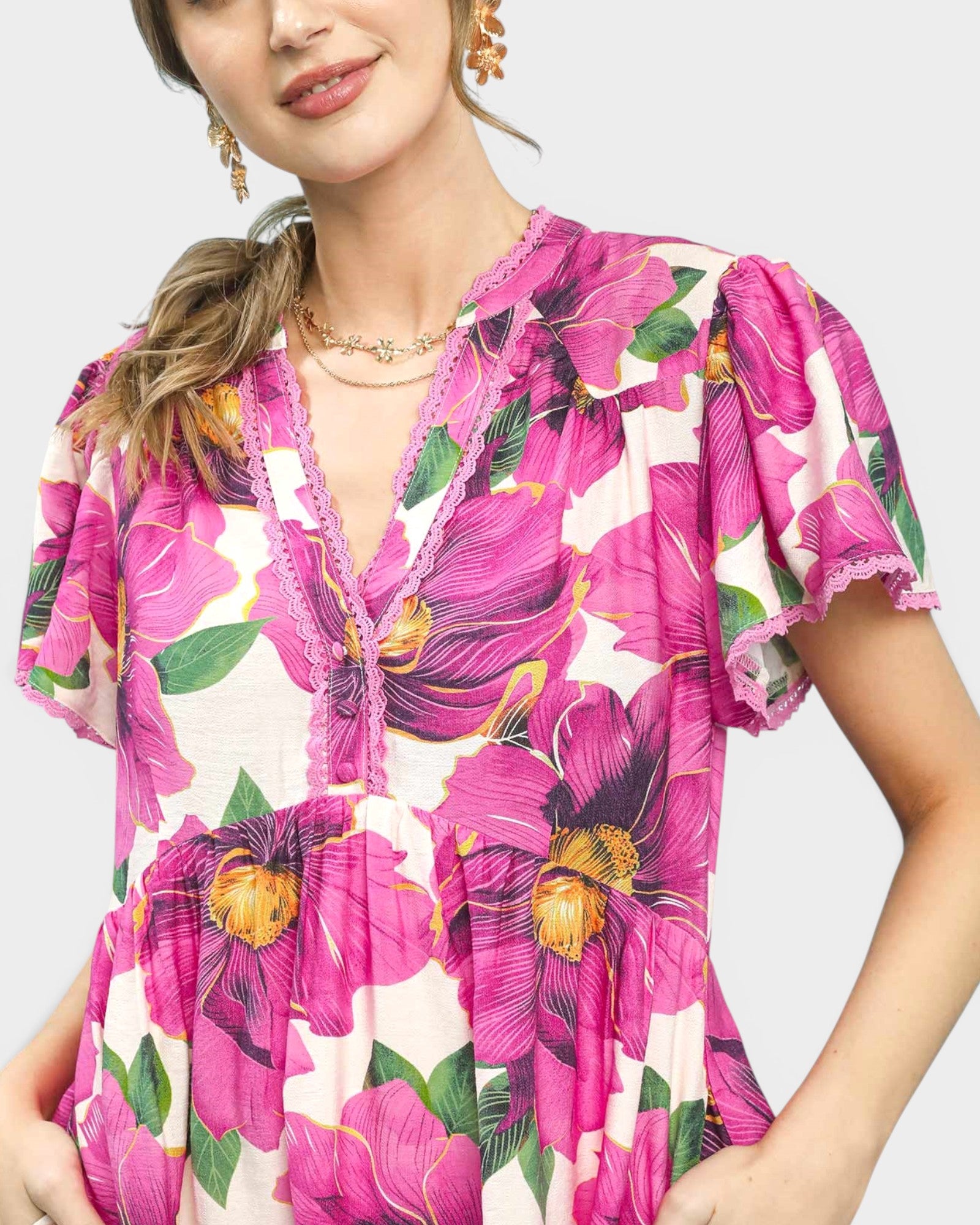 Woman wearing a vibrant floral dress with pink flowers on a plain background