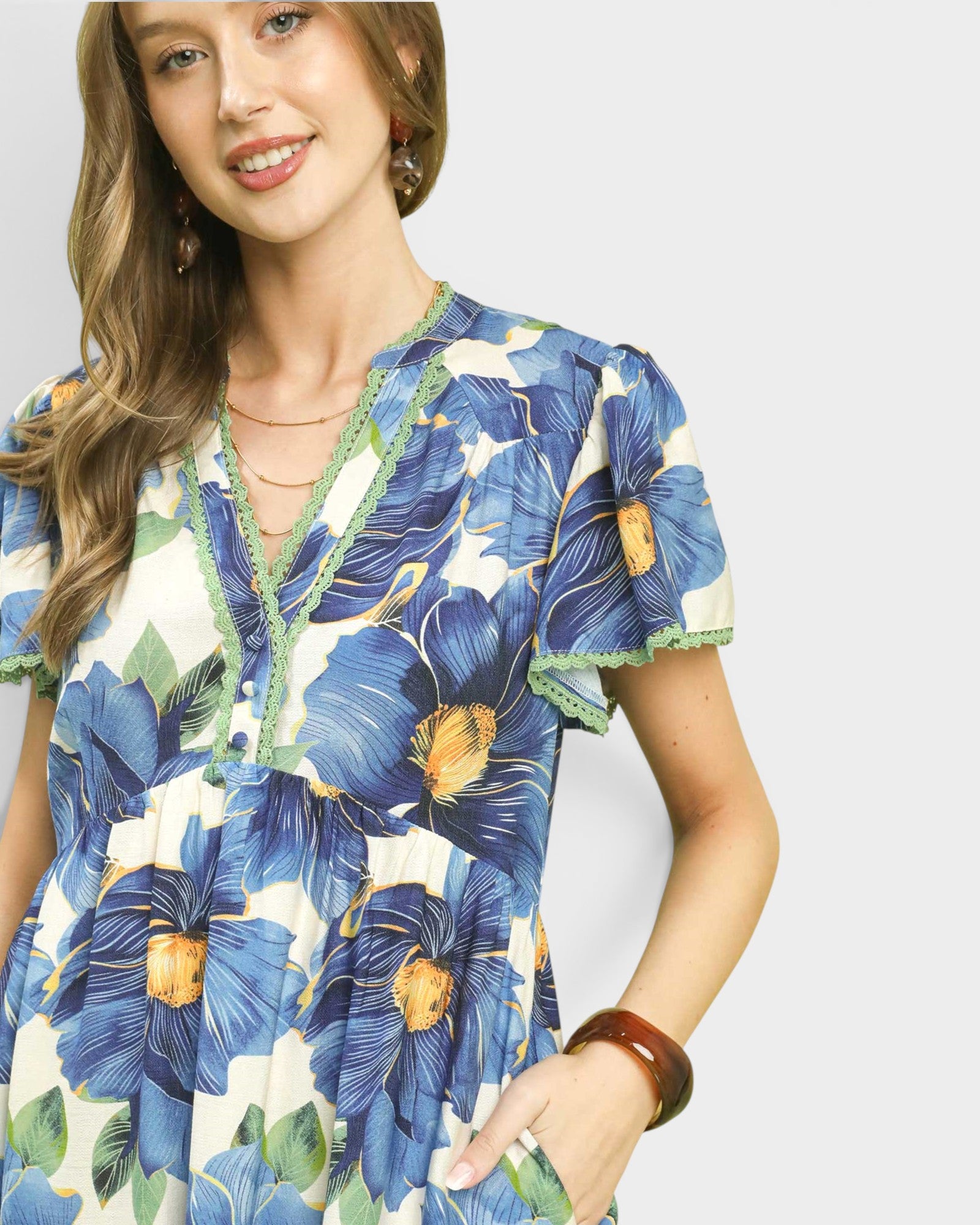 Woman wearing a blue floral dress against a plain background
