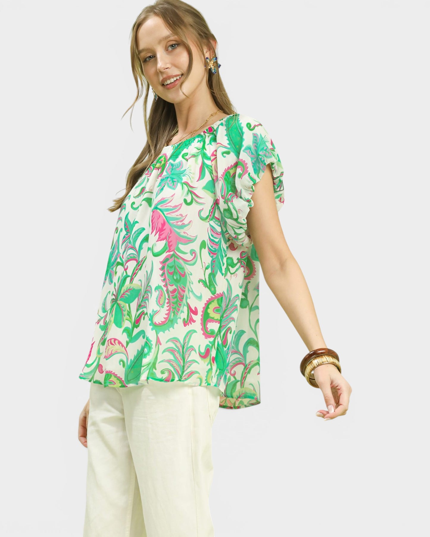 Woman wearing a colorful patterned blouse with a plain background