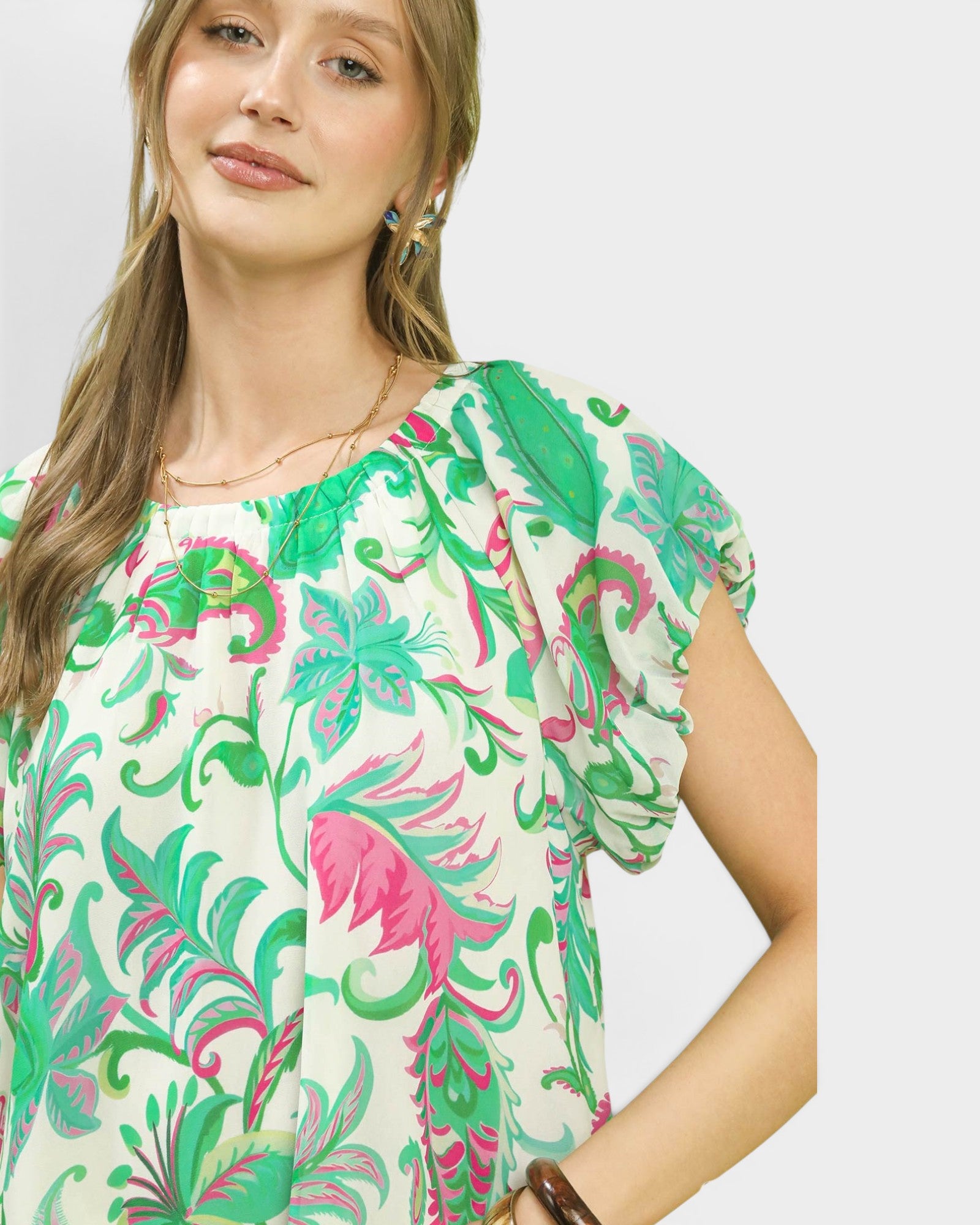 Woman wearing a colorful floral blouse against a plain background