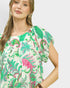 Woman wearing a colorful floral blouse against a plain background