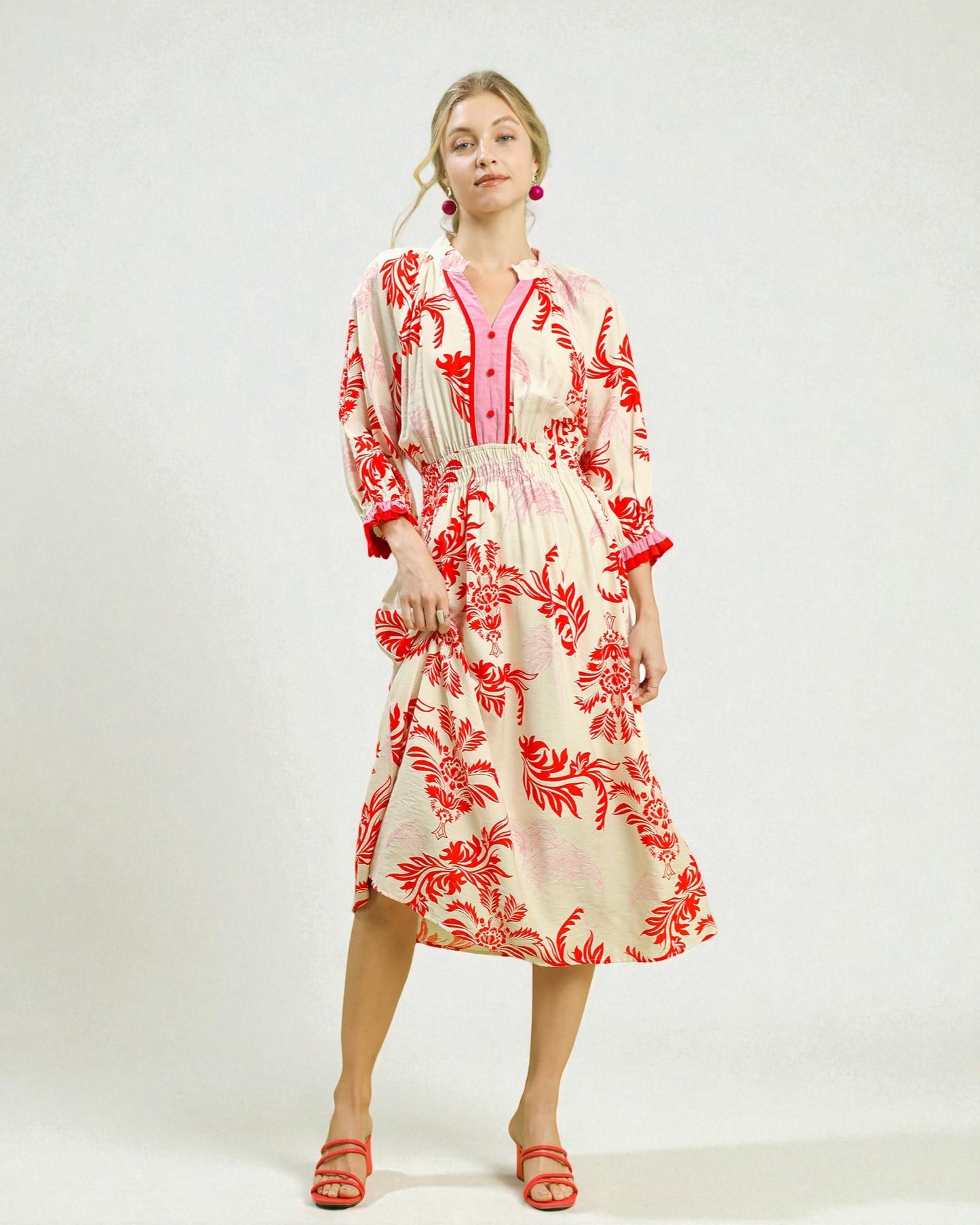 Woman wearing a red and white floral dress on a white background