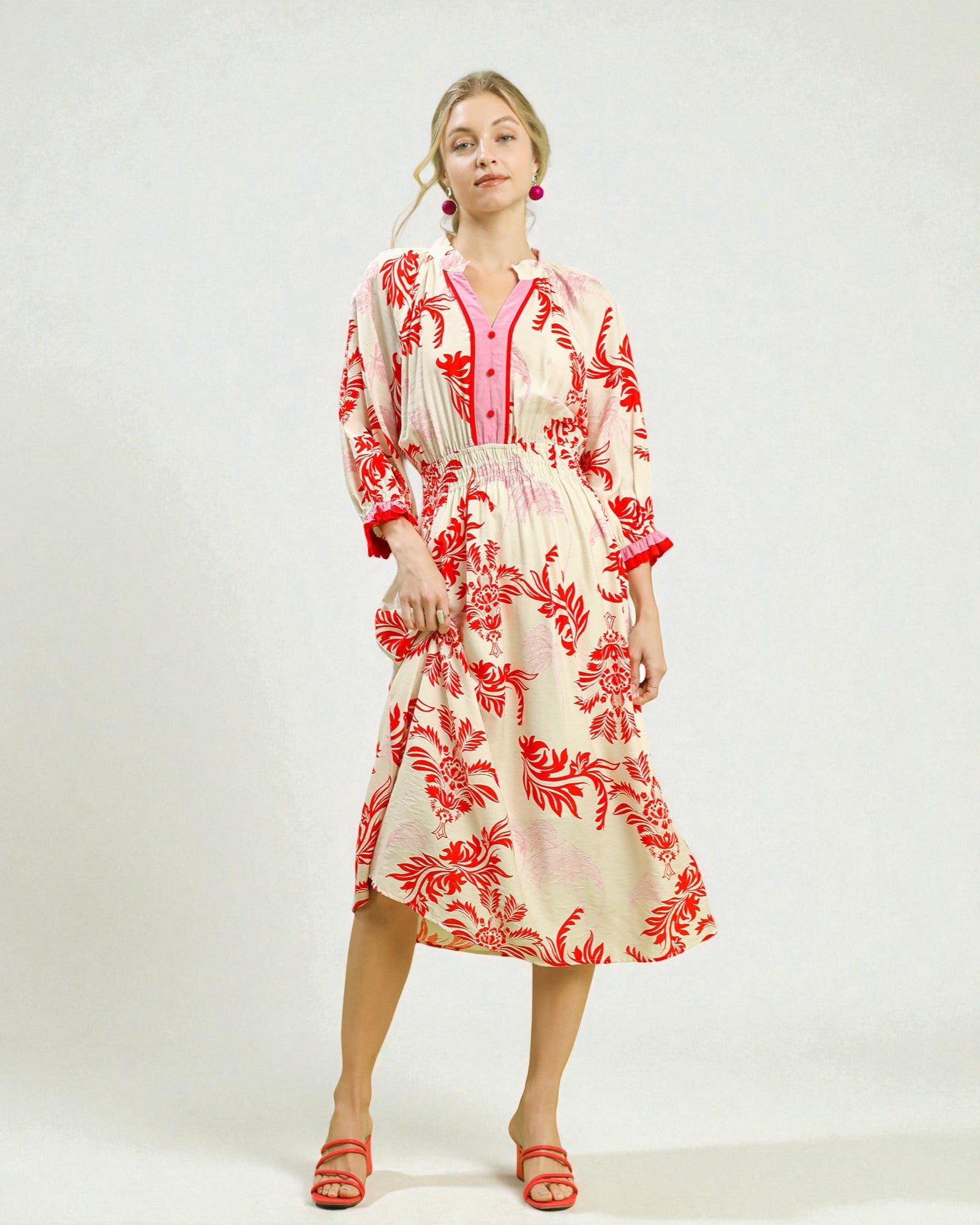 Woman wearing a red and white floral dress on a white background