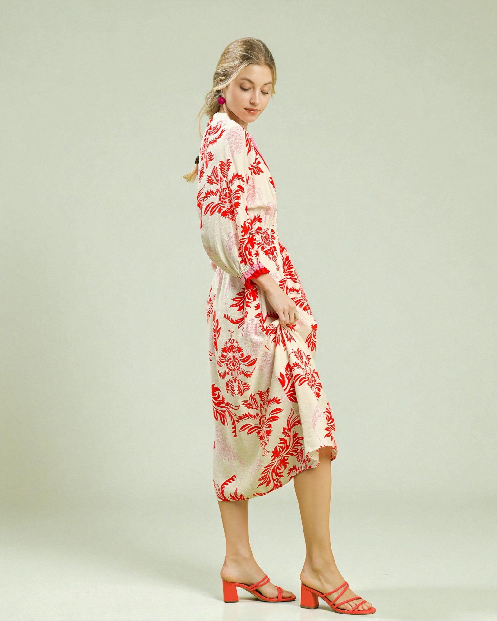 Woman wearing a red and white floral dress on a plain background