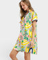 Woman wearing a colorful tropical print dress on a white background