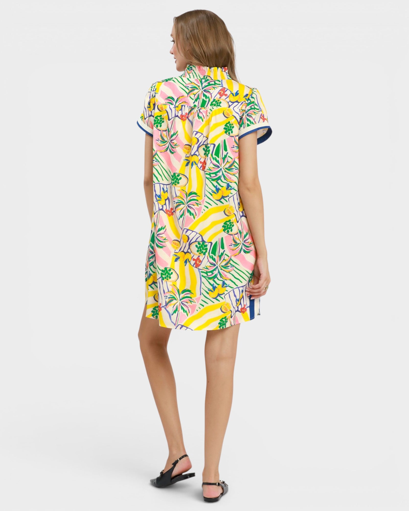 Woman wearing a colorful dress with a banana leaf pattern on a white background