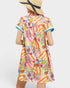 Woman wearing a colorful patterned dress with a straw hat on a white background