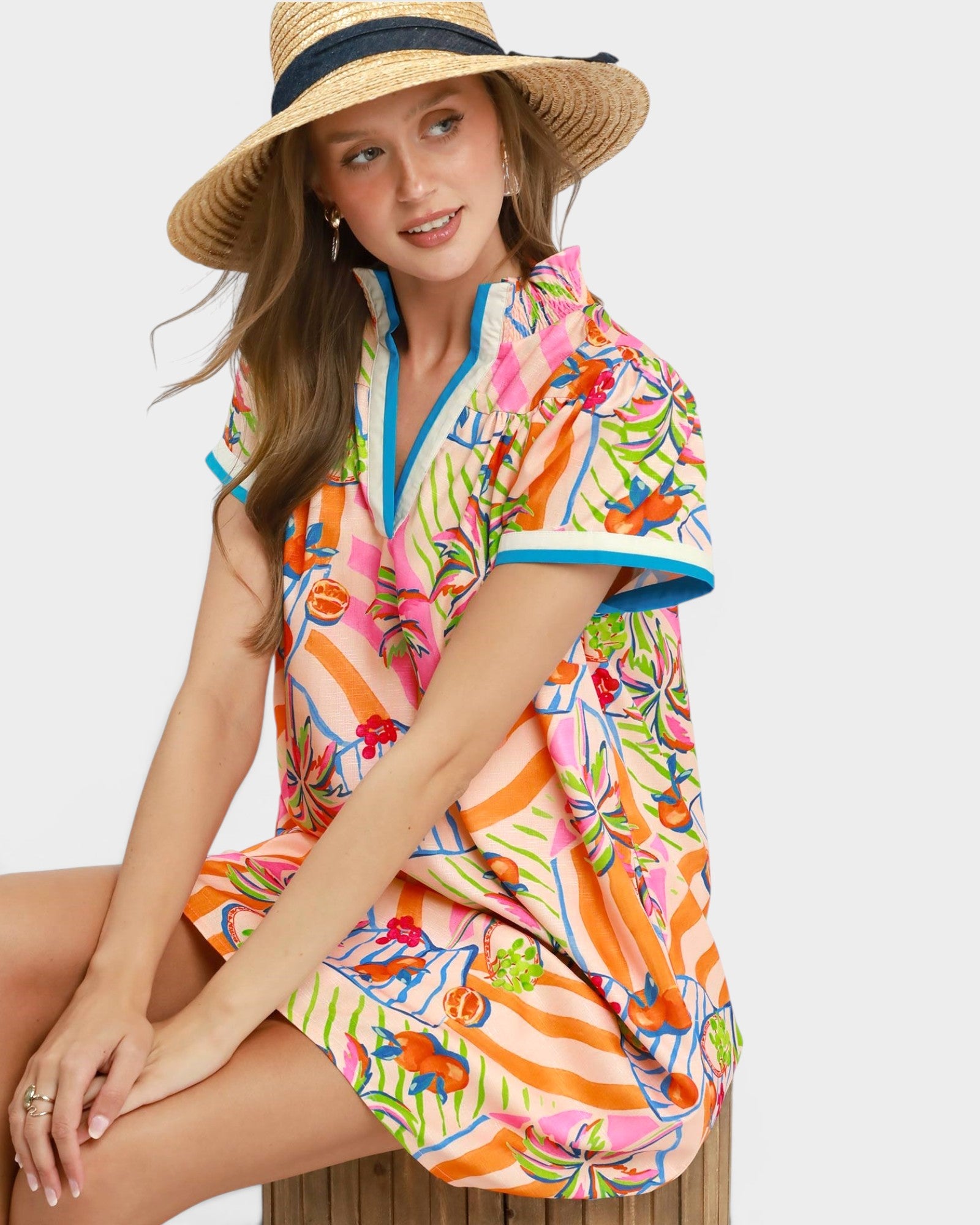 Woman wearing a colorful floral dress and straw hat on a white background