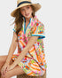 Woman wearing a colorful floral dress and straw hat on a white background