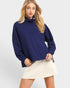 Woman wearing a navy blue sweater and white skirt on a light gray background