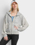 Woman wearing a gray zip-up hoodie and black pants on a white background
