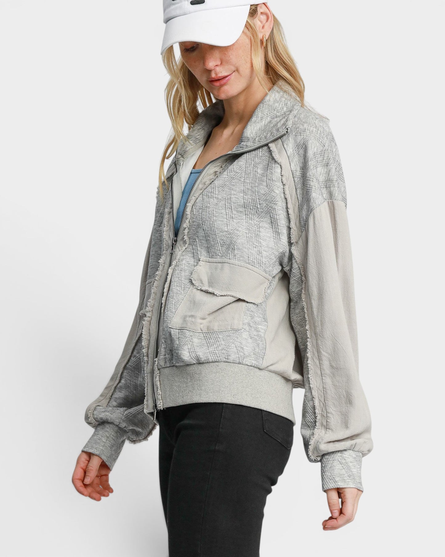 Woman wearing a gray zip-up hoodie with a white background
