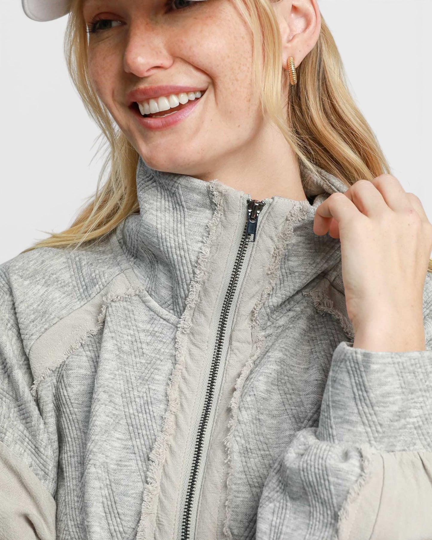 Woman wearing a textured gray jacket with a neutral background