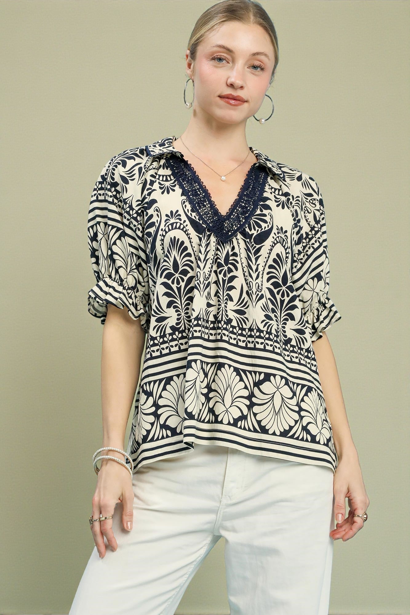 Woman wearing a patterned blouse with a V-neckline on a beige background
