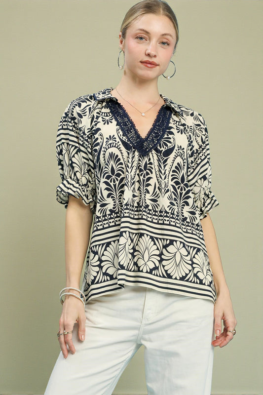 Woman wearing a patterned blouse with a V-neckline on a beige background