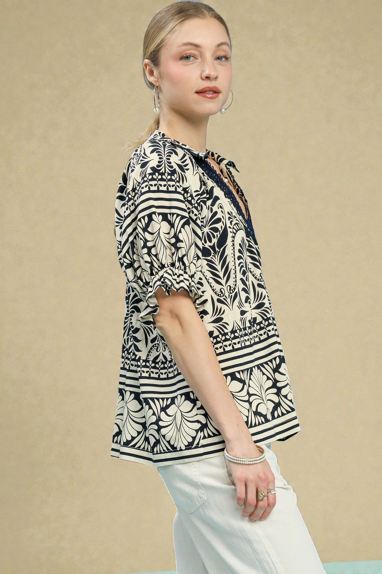 Woman wearing a black and white patterned blouse against a beige background