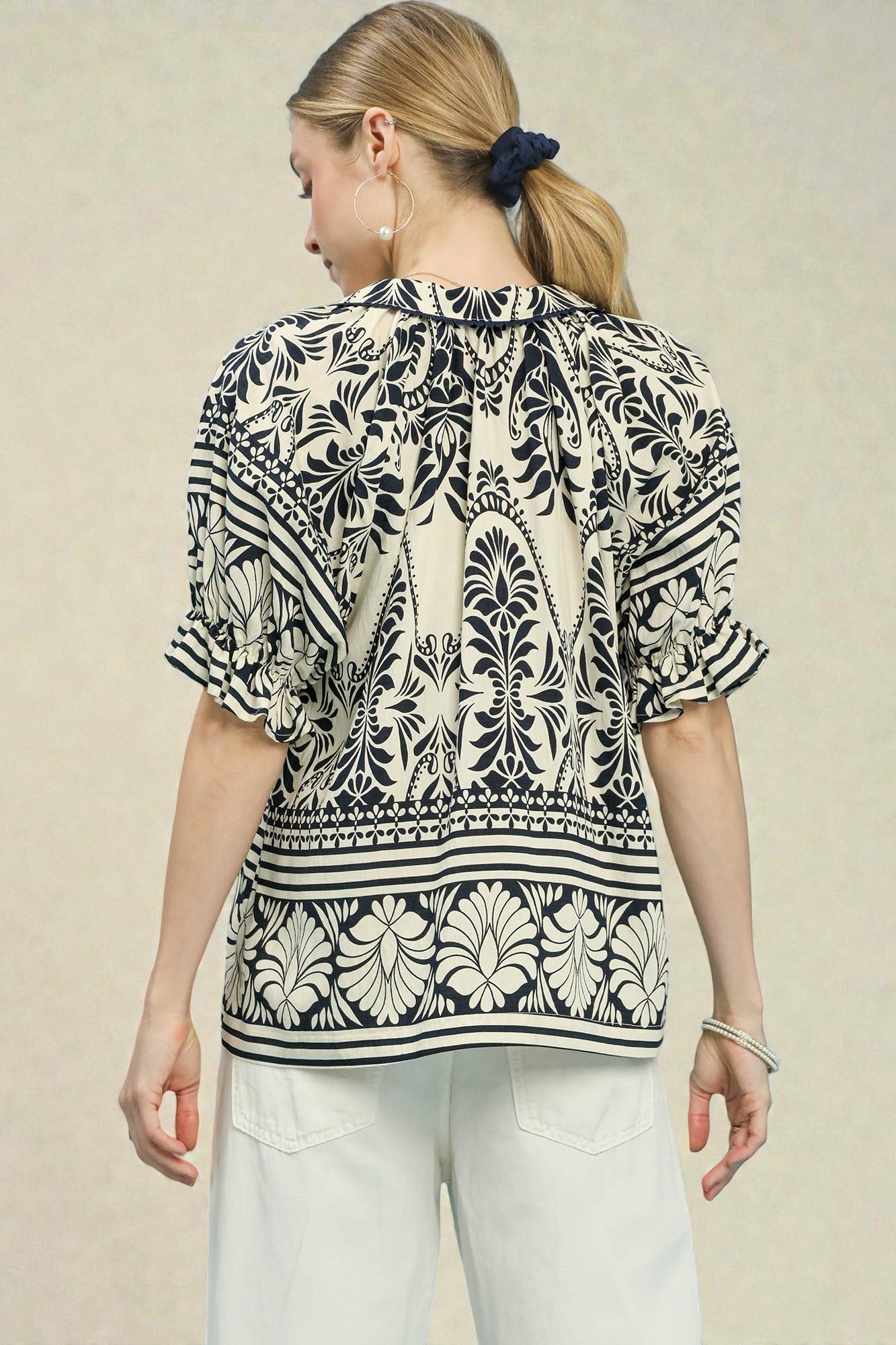 Woman wearing a black and white patterned blouse against a beige background